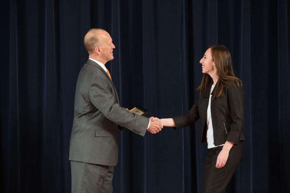 Doctor Potteiger shaking hands with an award recipient in a black blazer and white shirt